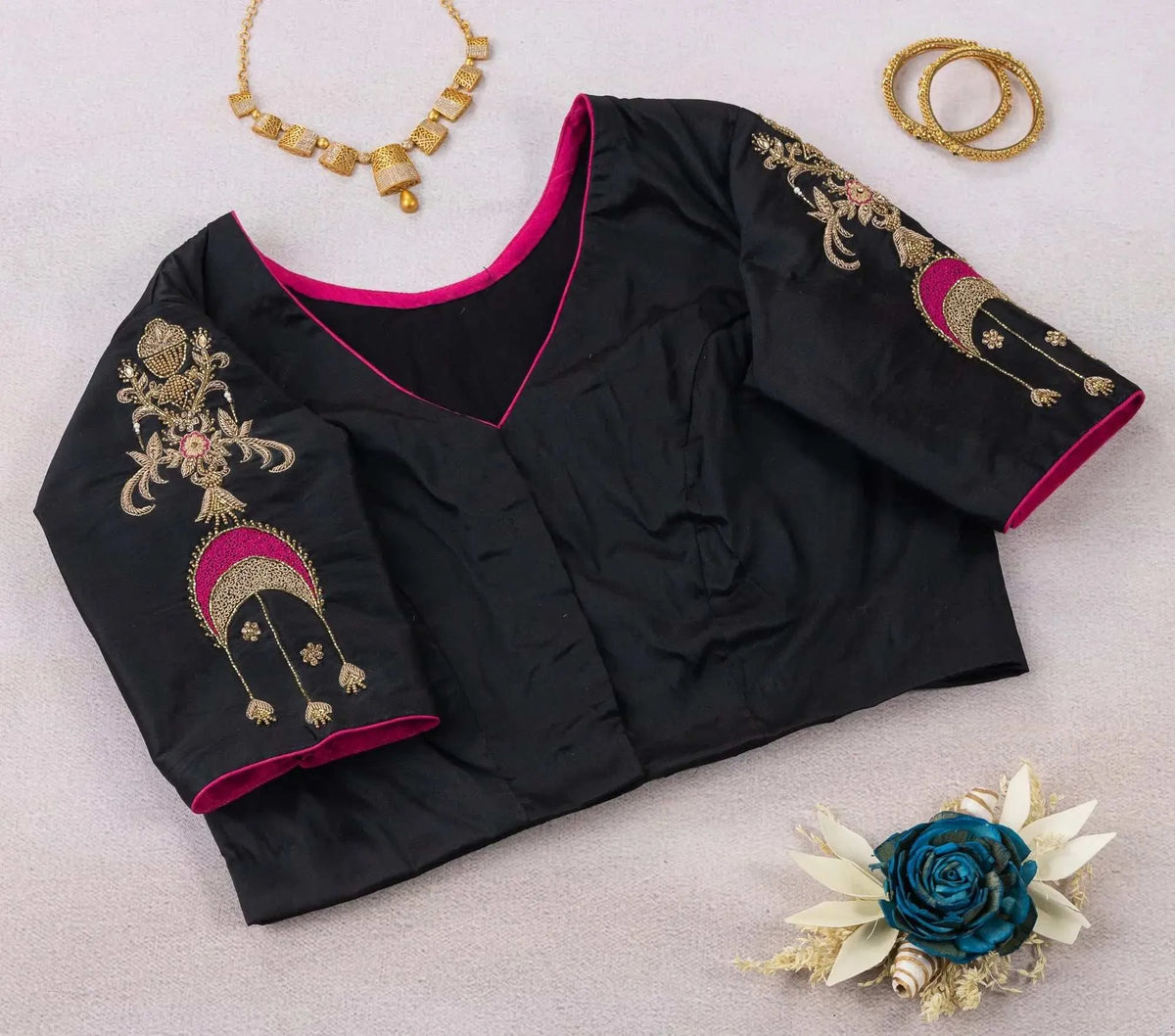 Plain front of the black blouse with pink-piped V neck, chand bali motifs on the sleeves