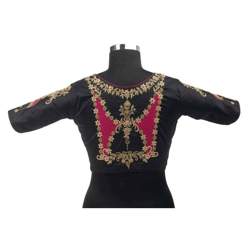Back of the black blouse on a bust form, gold zari and pink embroidery across the yoke