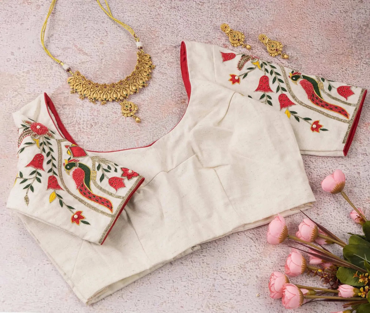 Front of the ivory blouse with red piped neckline and parrot embroidery on the sleeves