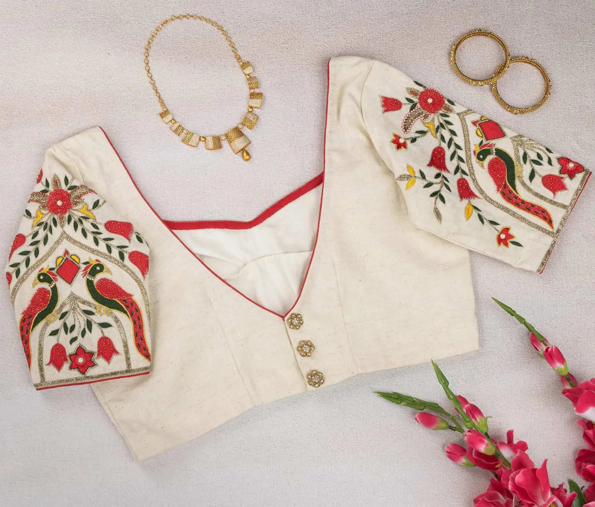 Ivory blouse flat-lay showing button back and embroidered sleeves, with gold necklace and bangles