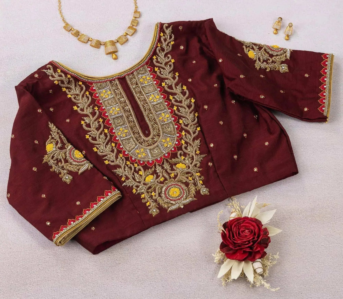 Maroon blouse styled flat with a jewellery set, zardozi panel and floral sleeve motifs
