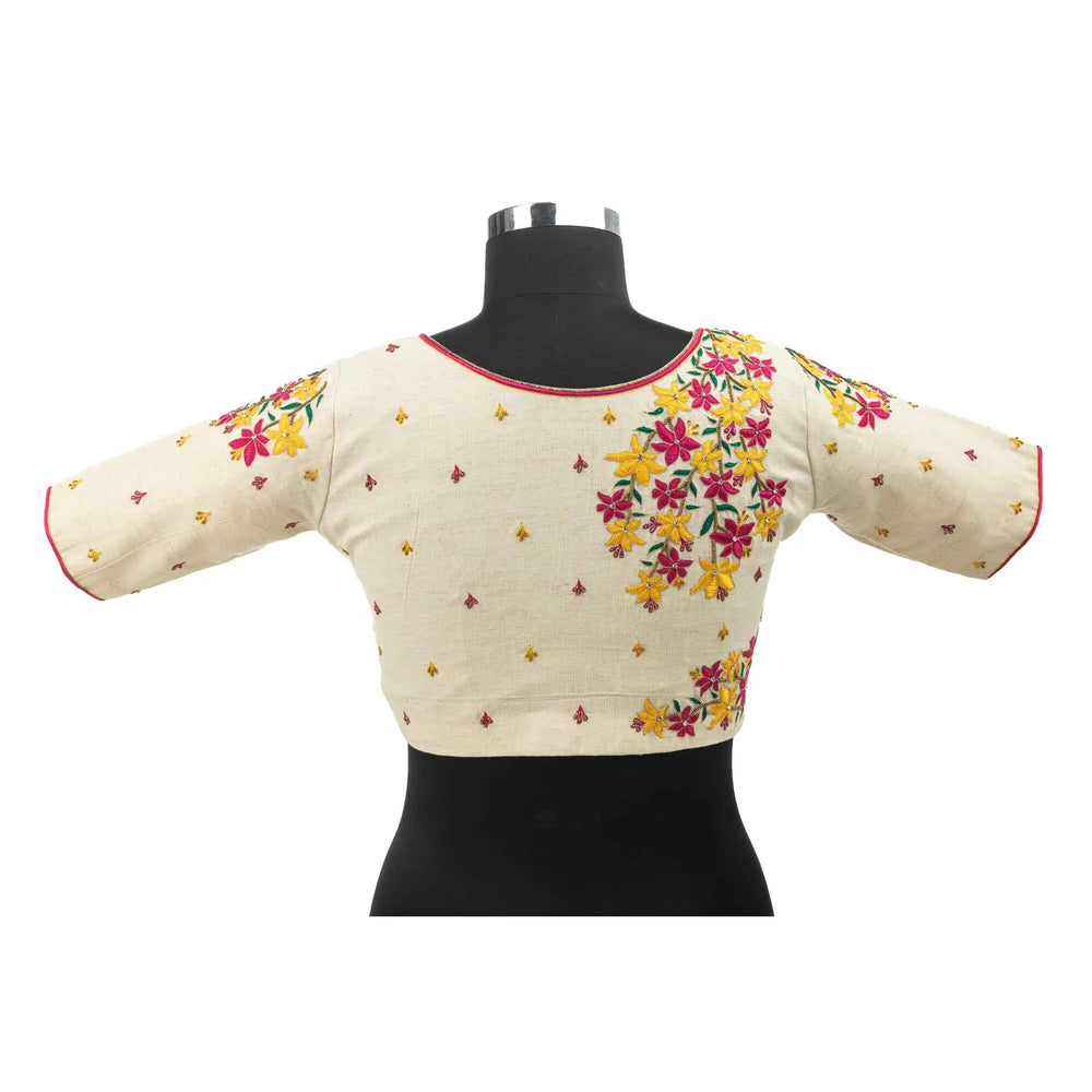 Back of the off-white blouse on a bust form, floral sprays over both shoulders