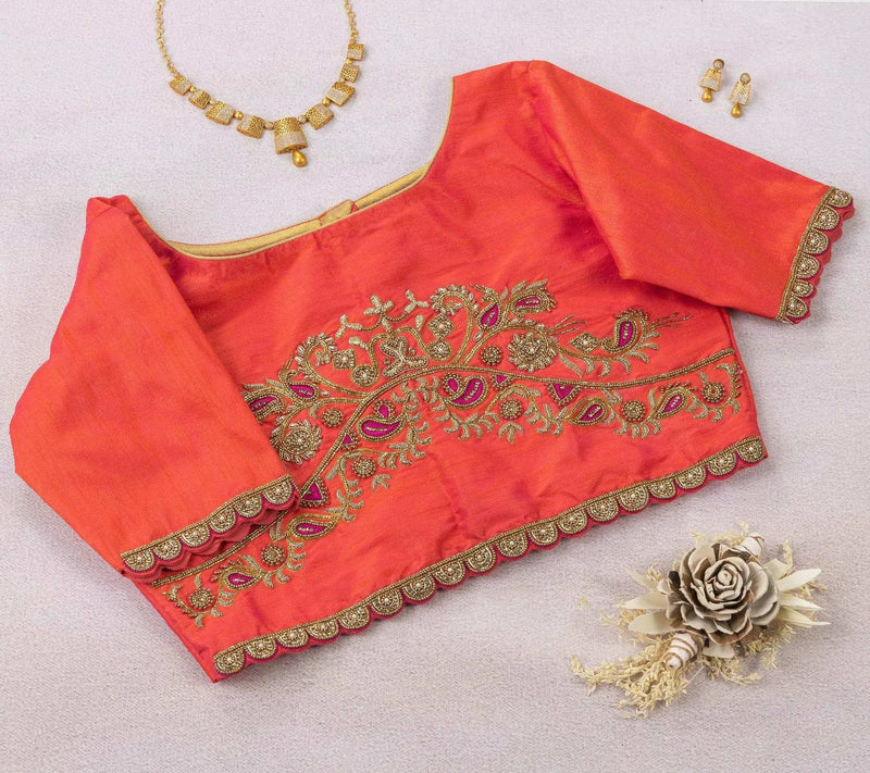 Coral orange blouse flat-laid back up, paisley zari work on show with a gold necklace and jhumkas