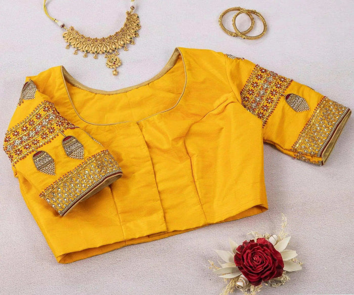 Plain front of the yellow blouse laid flat with embroidered sleeve bands and a rose alongside