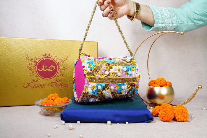 Bag held up by its gold chain, pink body and mosaic bead panel in view