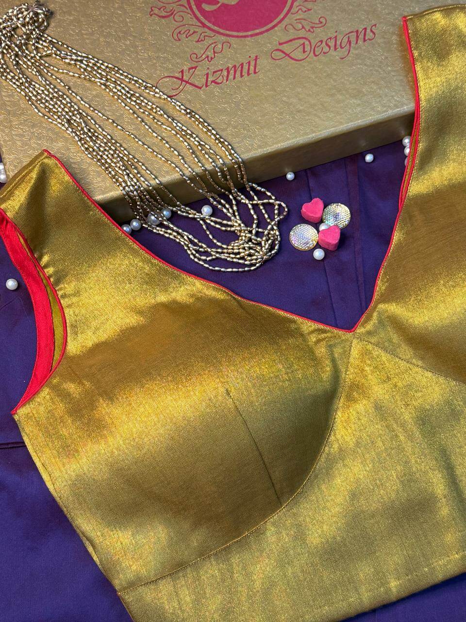 Red piping tracing the deep V neckline of the golden blouse, close-up