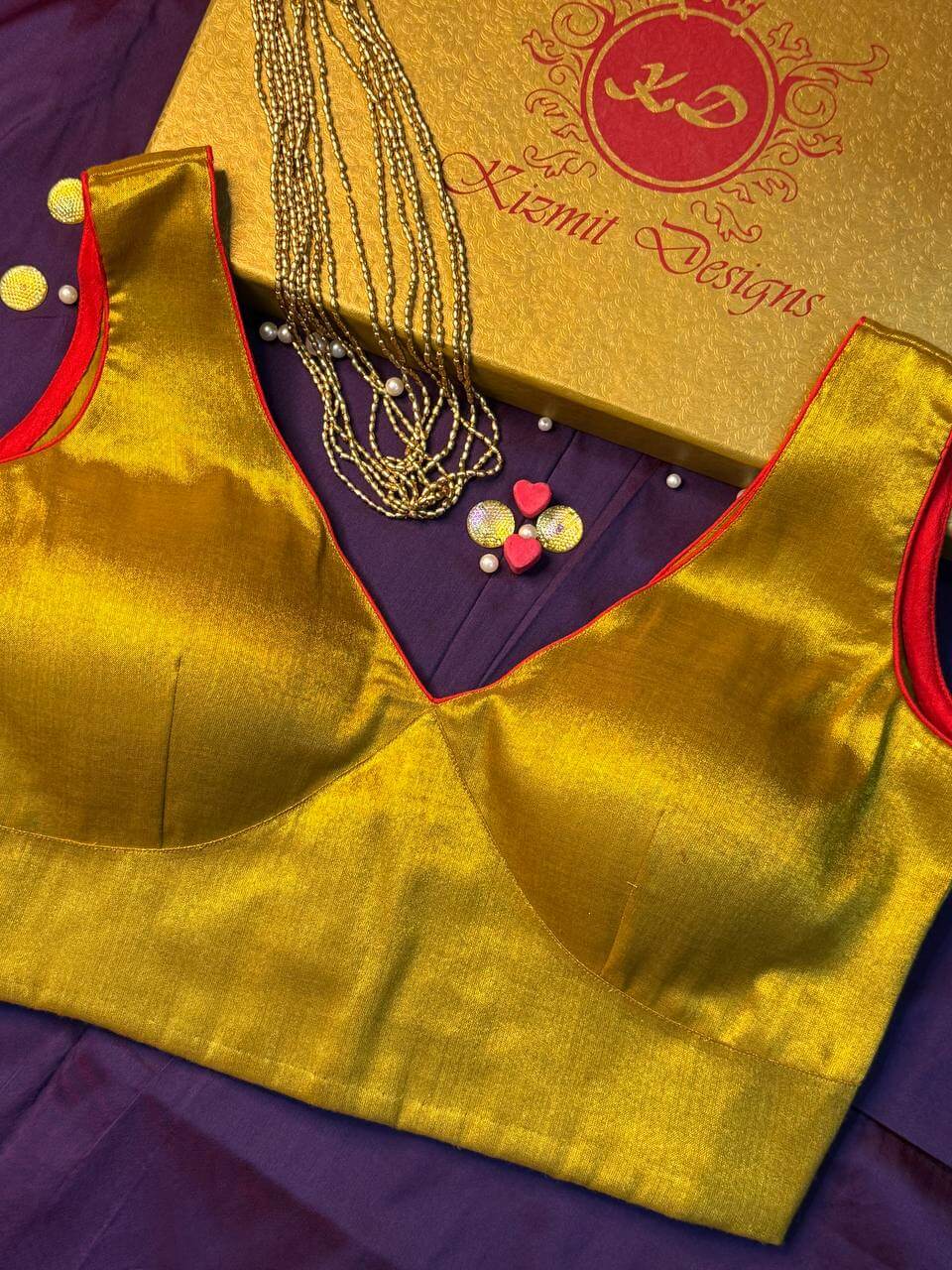 Fitted bust panels and pointed V neck of the gold blouse, seen at an angle