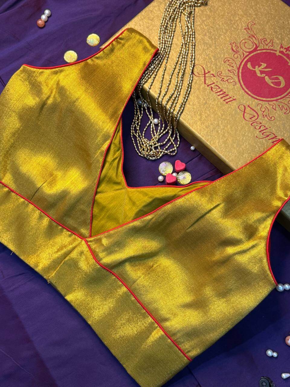 Side seam and V opening of the golden blouse, red piping along every edge