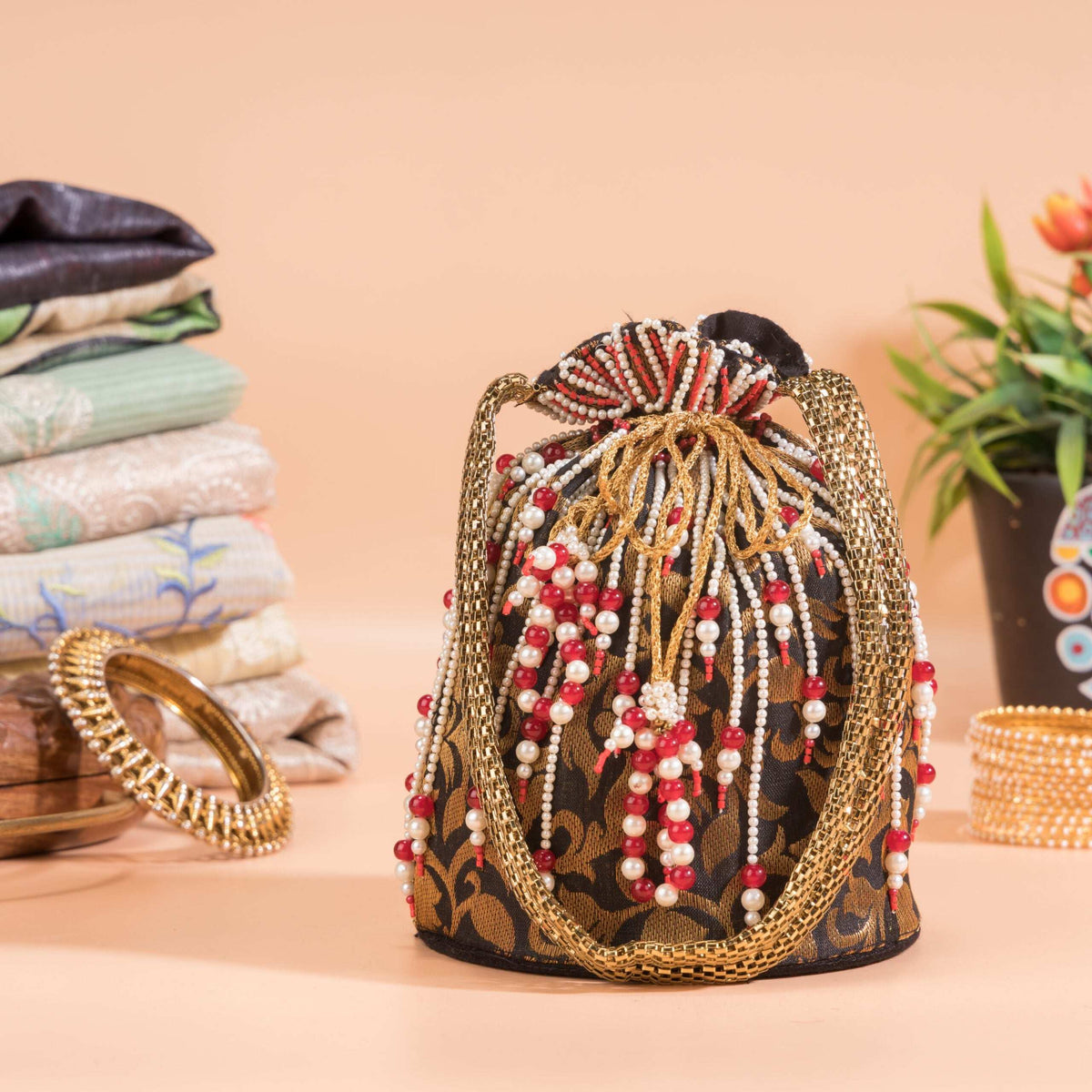 Red and pearl bead strands hanging from the drawstring of the black brocade potli