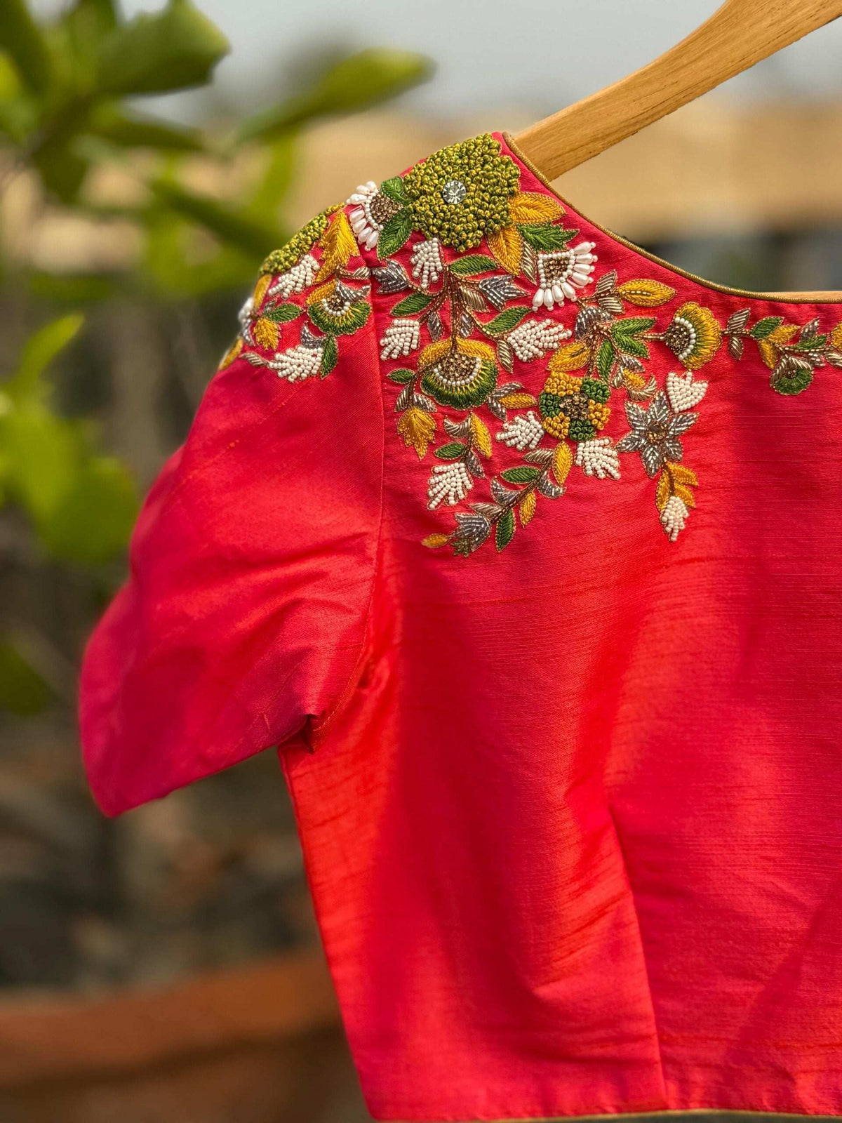 Close-up of beaded floral embroidery running across the shoulder of the pink blouse