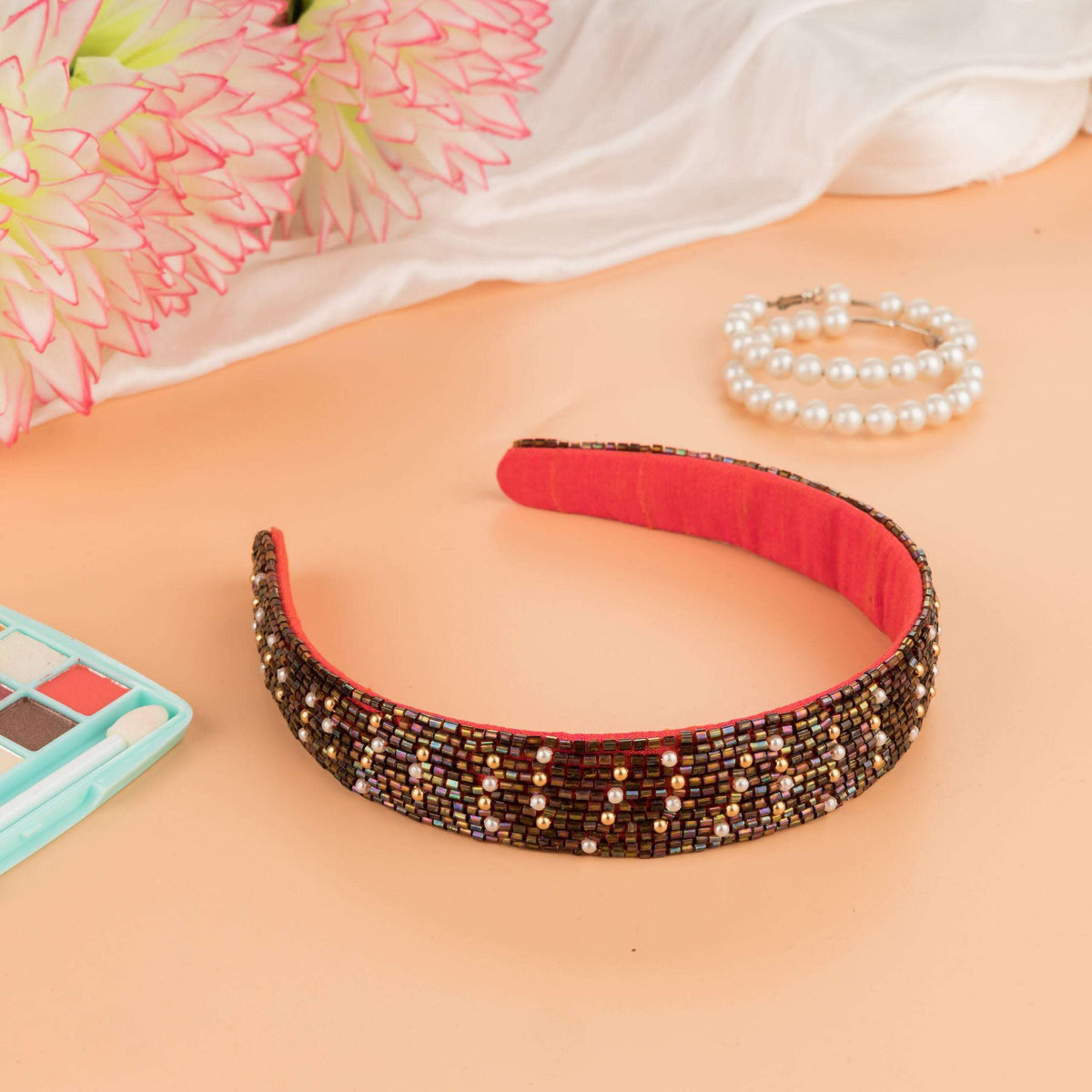 Bronze beaded headband with coral inner band, shown with pearls and a makeup palette