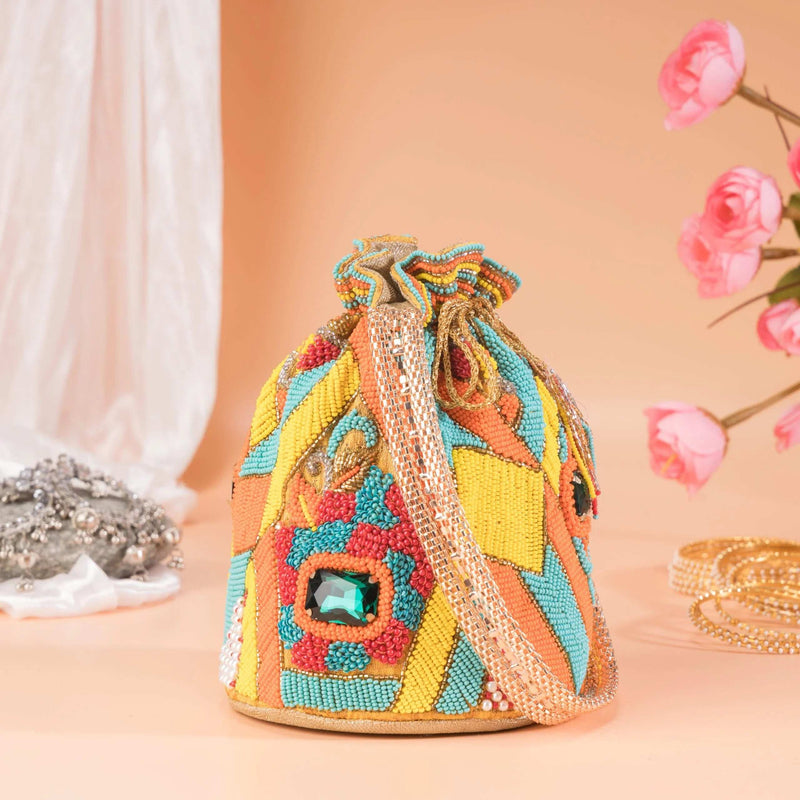 Chrome yellow beaded potli bag with a green stone, styled with pink blooms and bangles