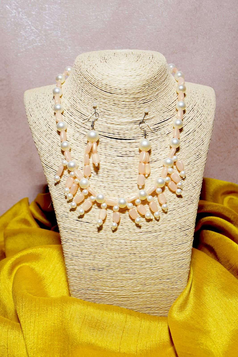 Coral and pearl bead necklace with matching drop earrings on a woven display bust