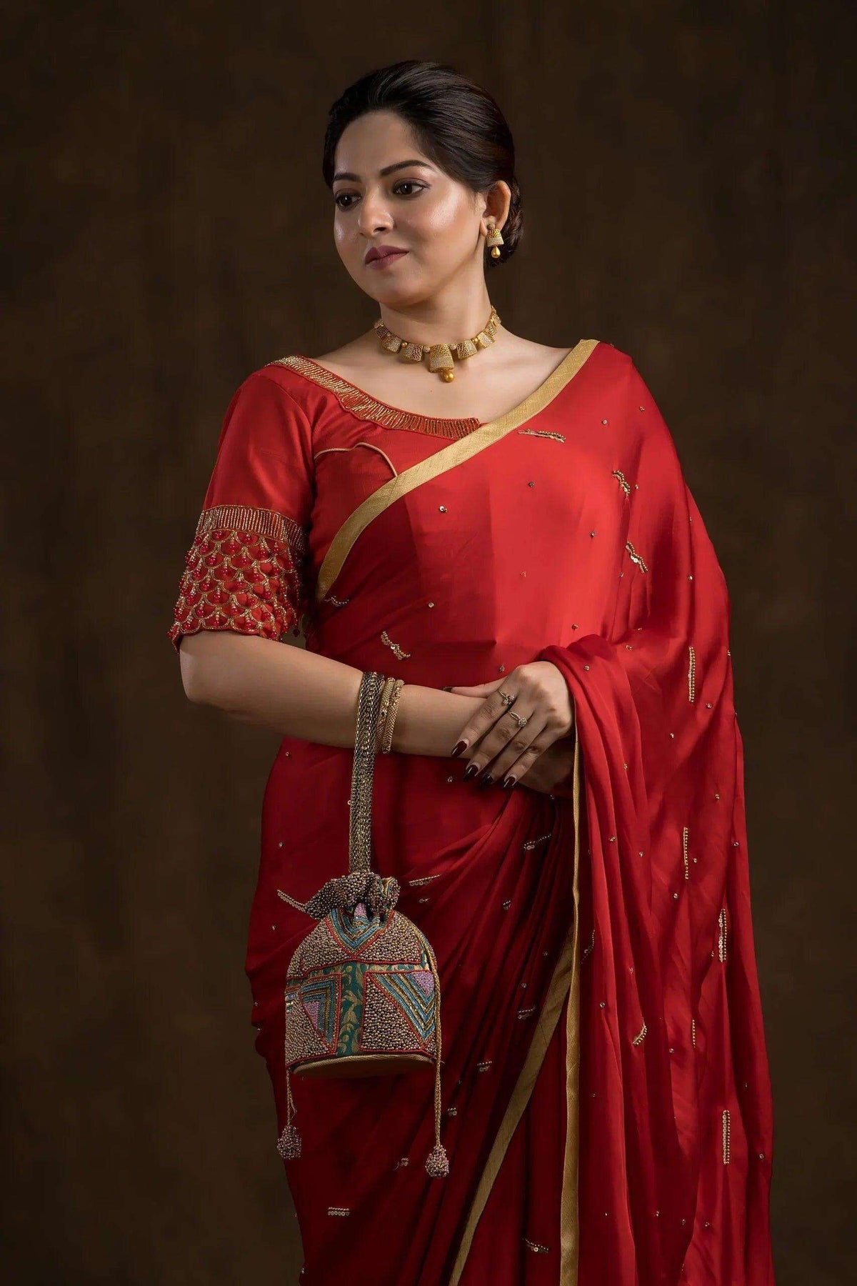 Crimson blouse worn with a red saree, neckline and bead-worked sleeve in view