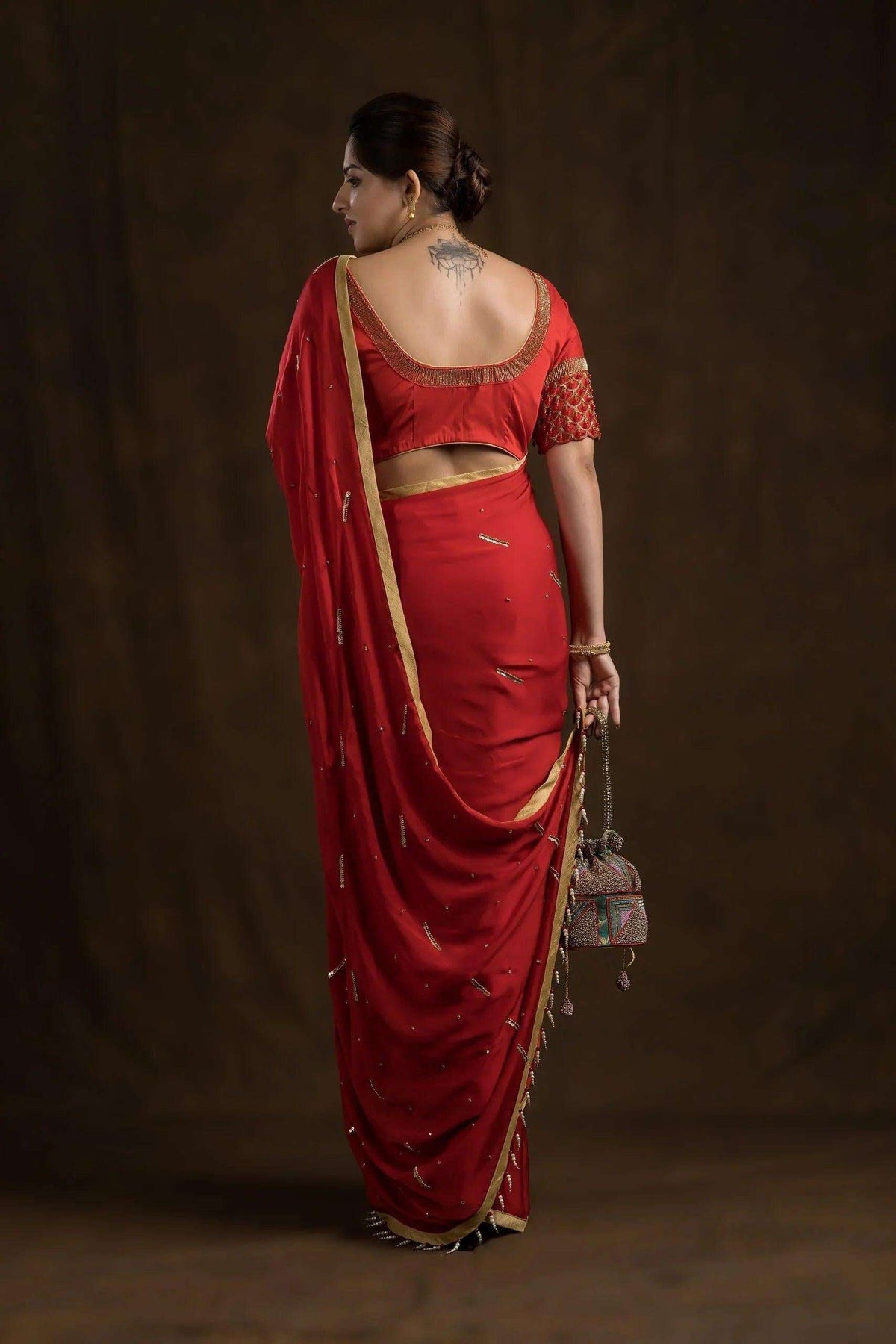 Back view of the deep scooped crimson blouse trimmed in gold, worn with a red saree