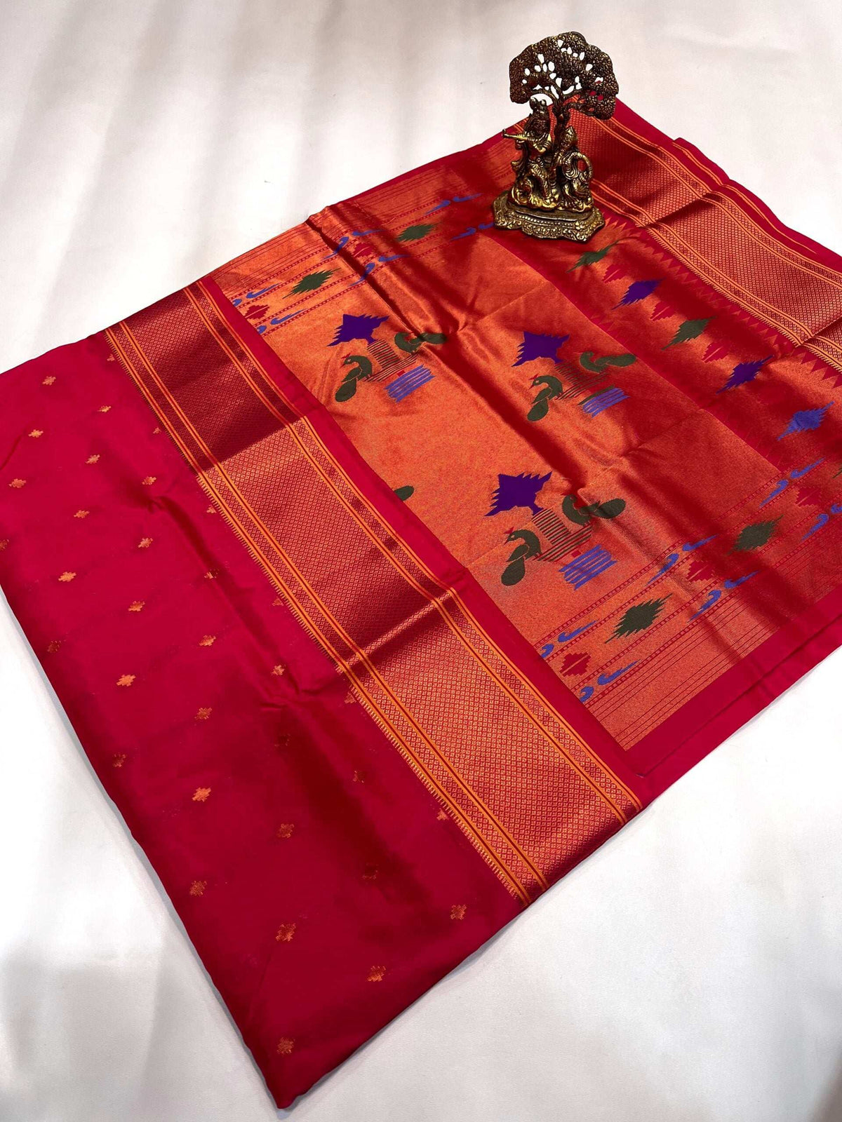 Rani pink Paithani with gold pallu, peacock and lotus motifs, brass Ganesha beside