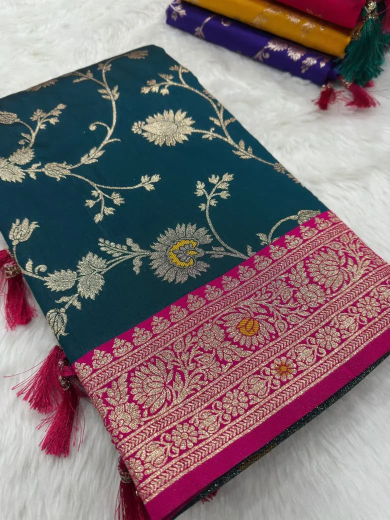Teal saree folded flat with gold jaal on the body and a pink brocade border with tassels