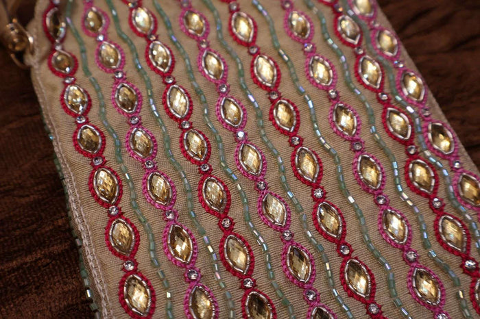 Close-up of the sling bag's mirror and bead work in red, pink and gold rows