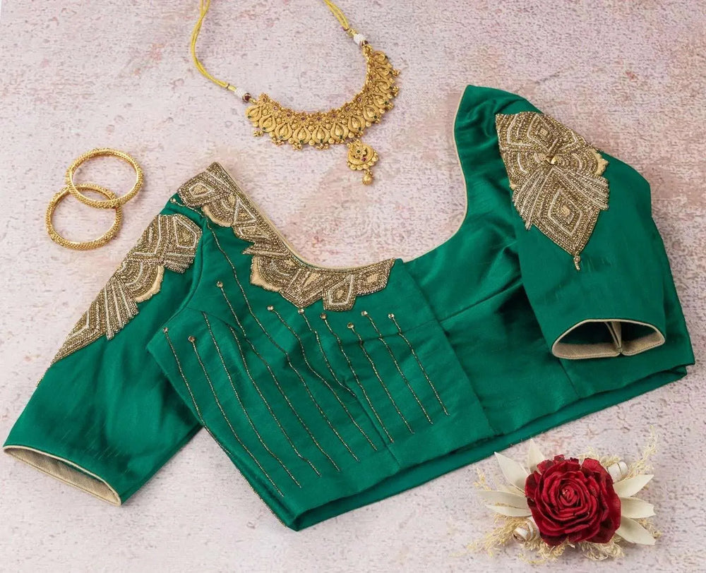 Emerald green blouse flat-laid with a gold necklace and bangles alongside