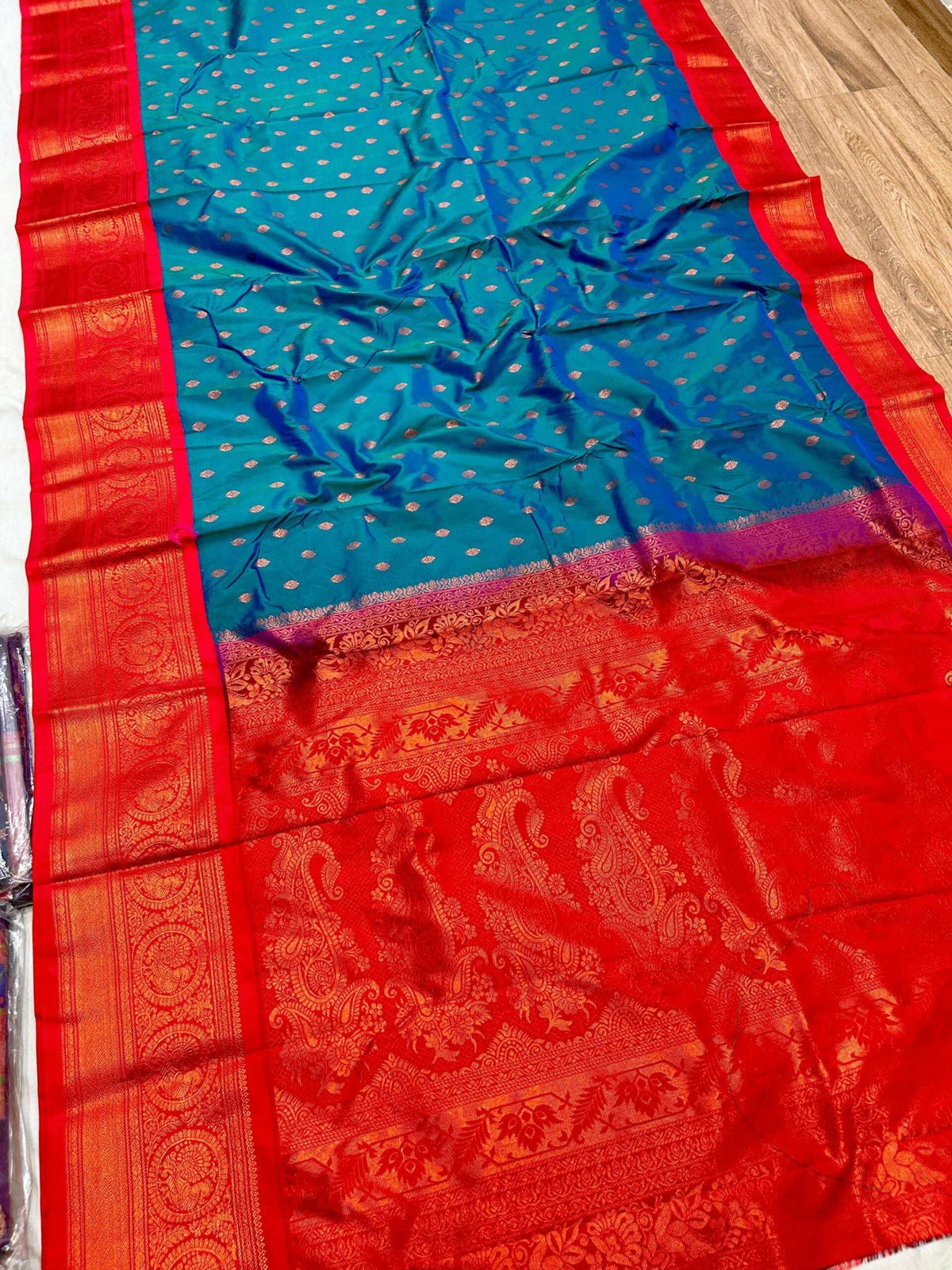Red zari border and pallu of the teal Gadwal Paithani spread out flat