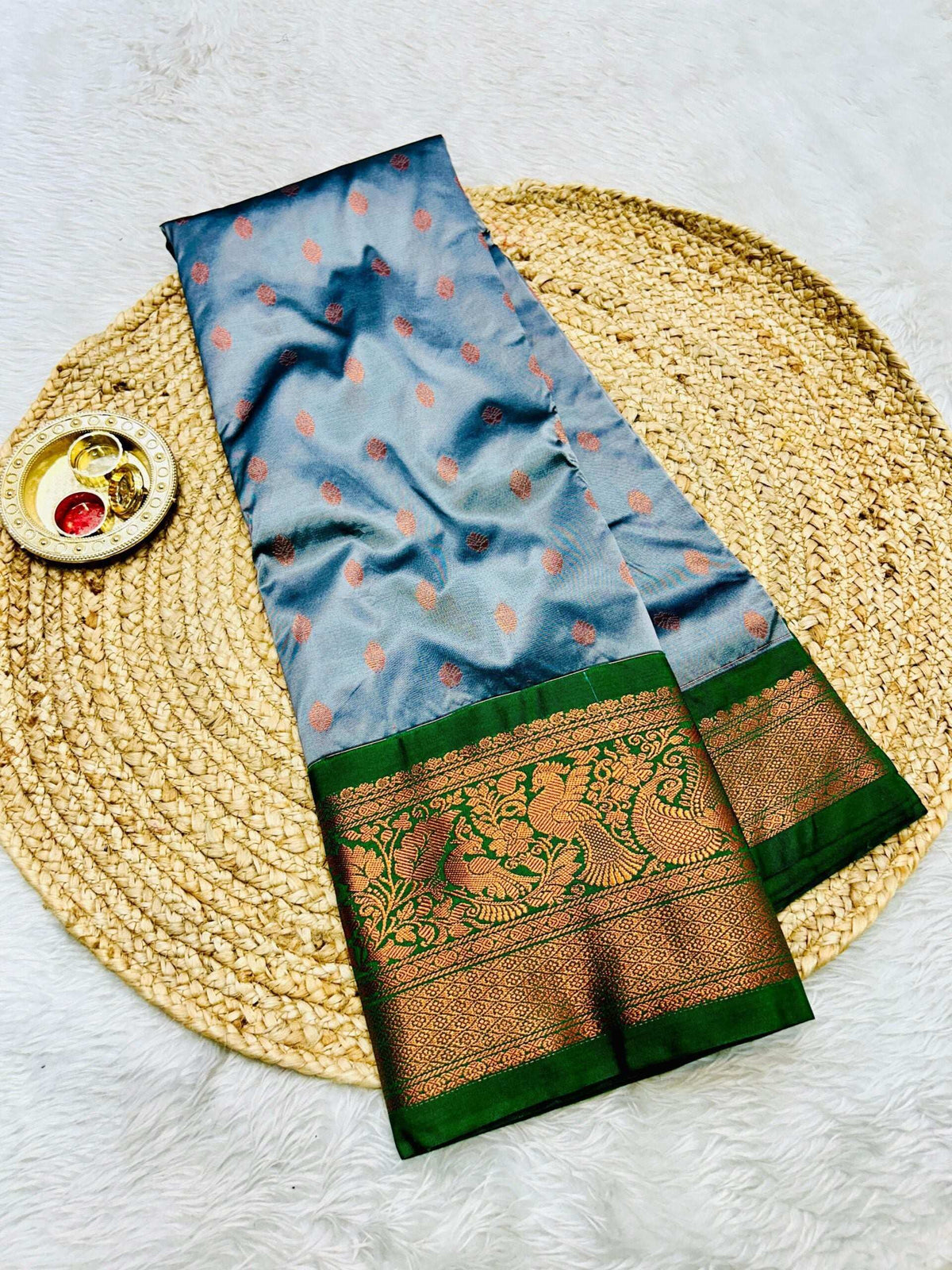 Grey brocade saree with copper bootis and a bottle green zari peacock border