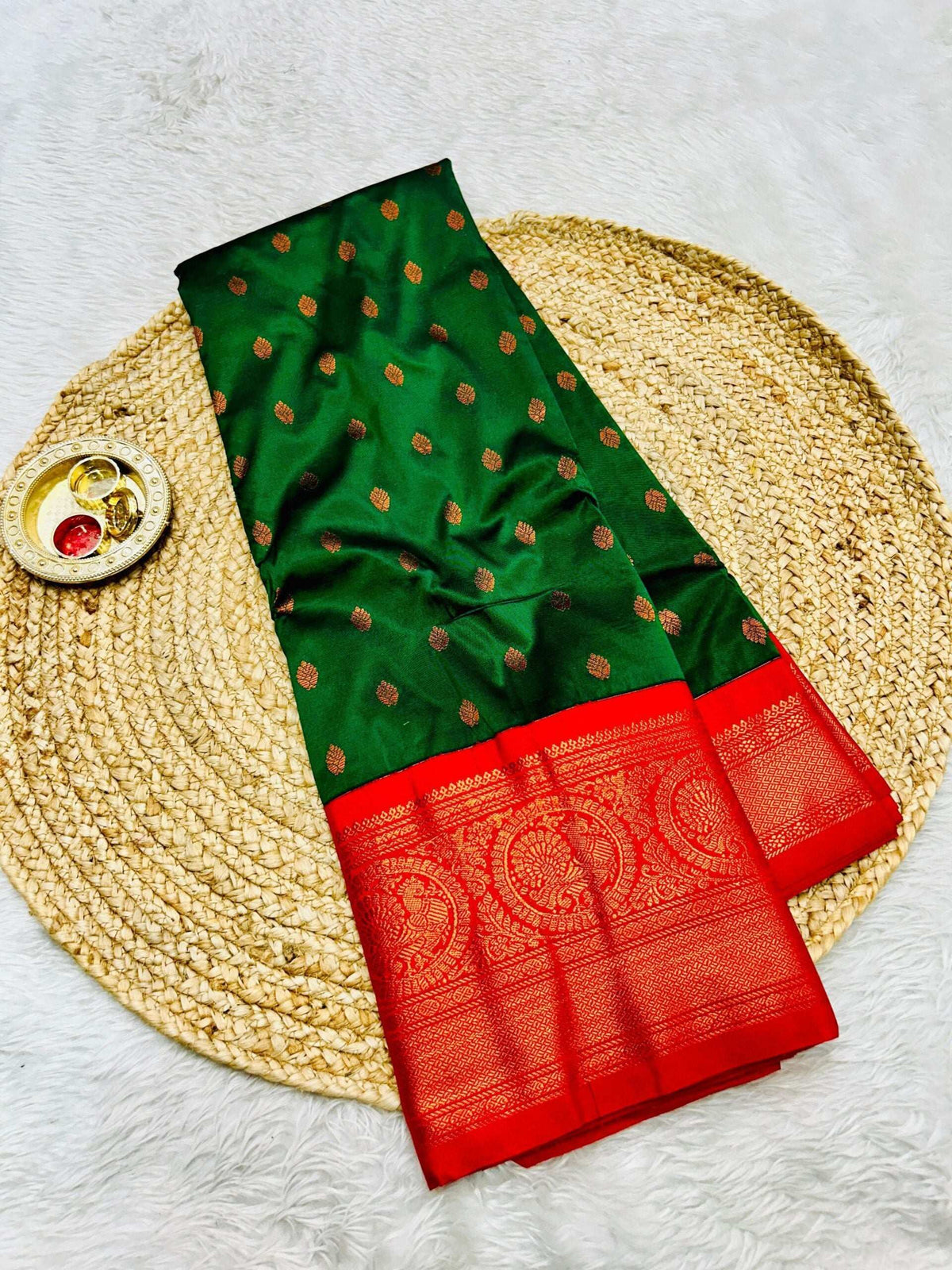 Bottle green saree body with copper bootis beside a red zari brocade border
