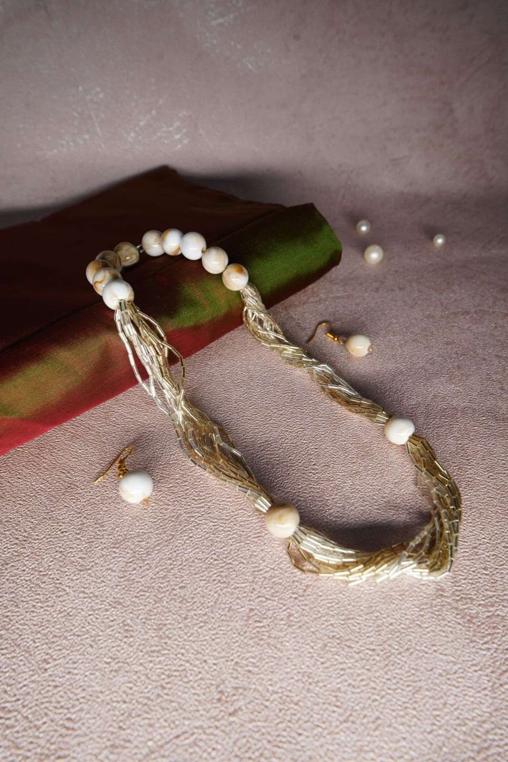 Twisted gold strands and round ivory beads shot at an angle with loose pearls