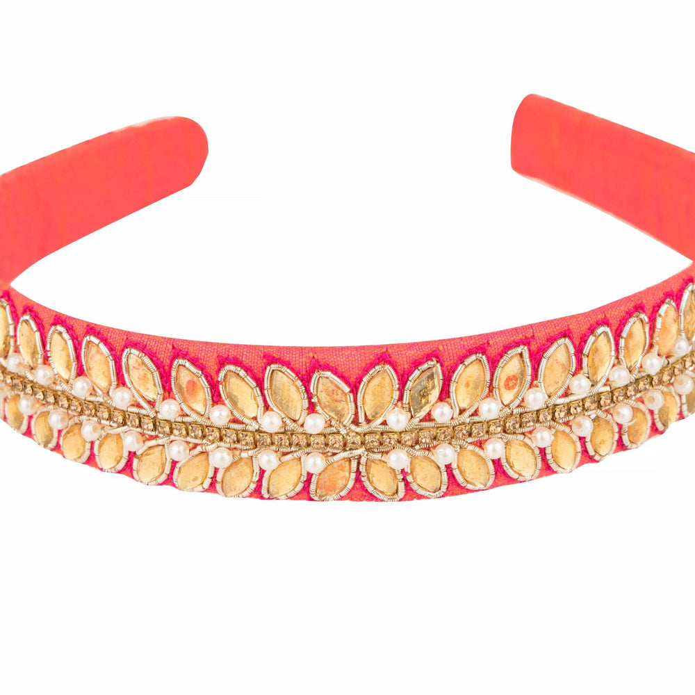 Close-up of golden leaf stones and pearl rows along the pink fabric headband