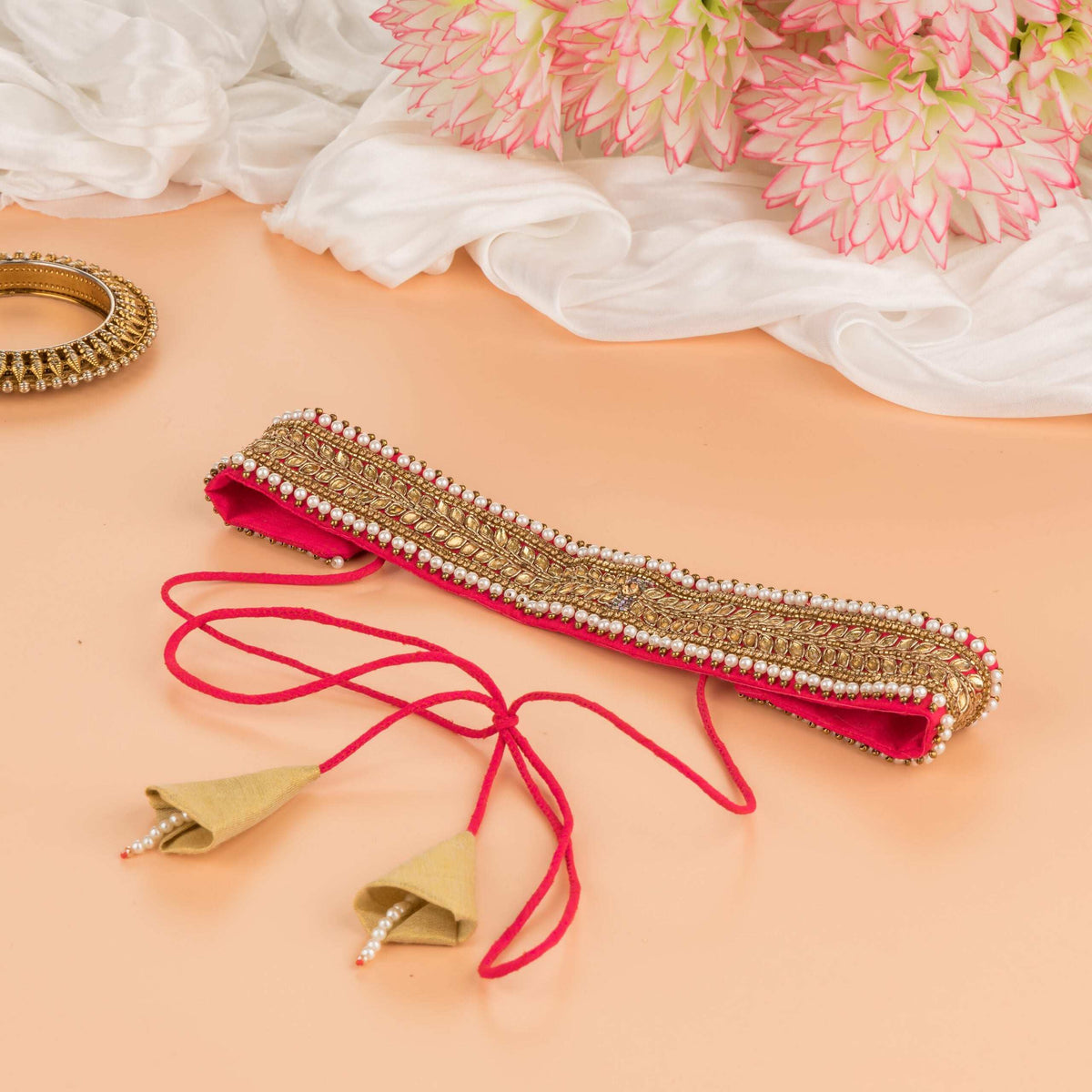 Pink embellished saree belt on peach with cords and gold cone tassels trailing