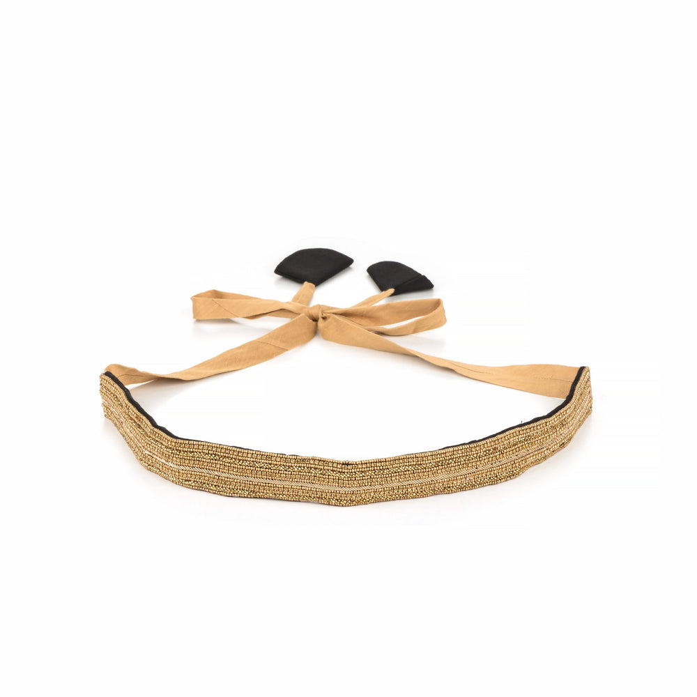 Golden beaded saree belt laid flat with beige tie ribbon and black leaf-shaped ends