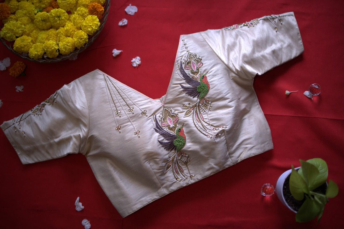Ivory Gulnaz blouse flat on red cloth, bird and lotus embroidery across the front