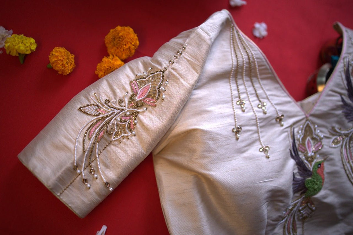 Sleeve embroidery close-up with pink lotus motif and small hanging bead drops