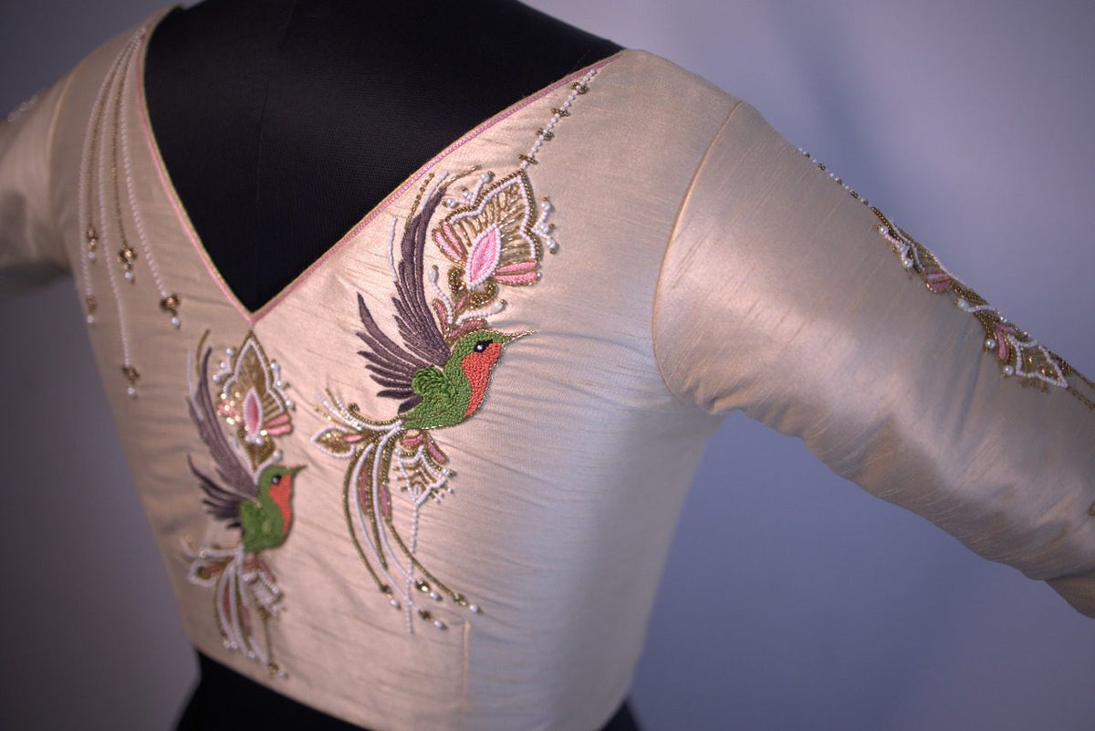 Blouse on a bust form showing the V neckline and green and red bird motifs
