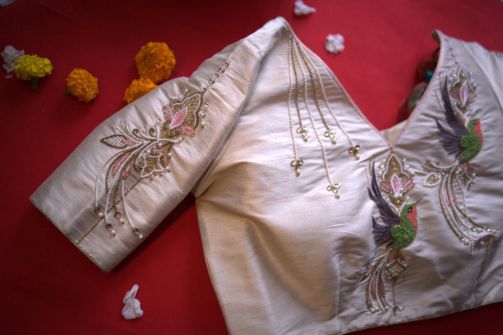 Folded sleeve and neckline of the ivory blouse laid on red with marigold flowers