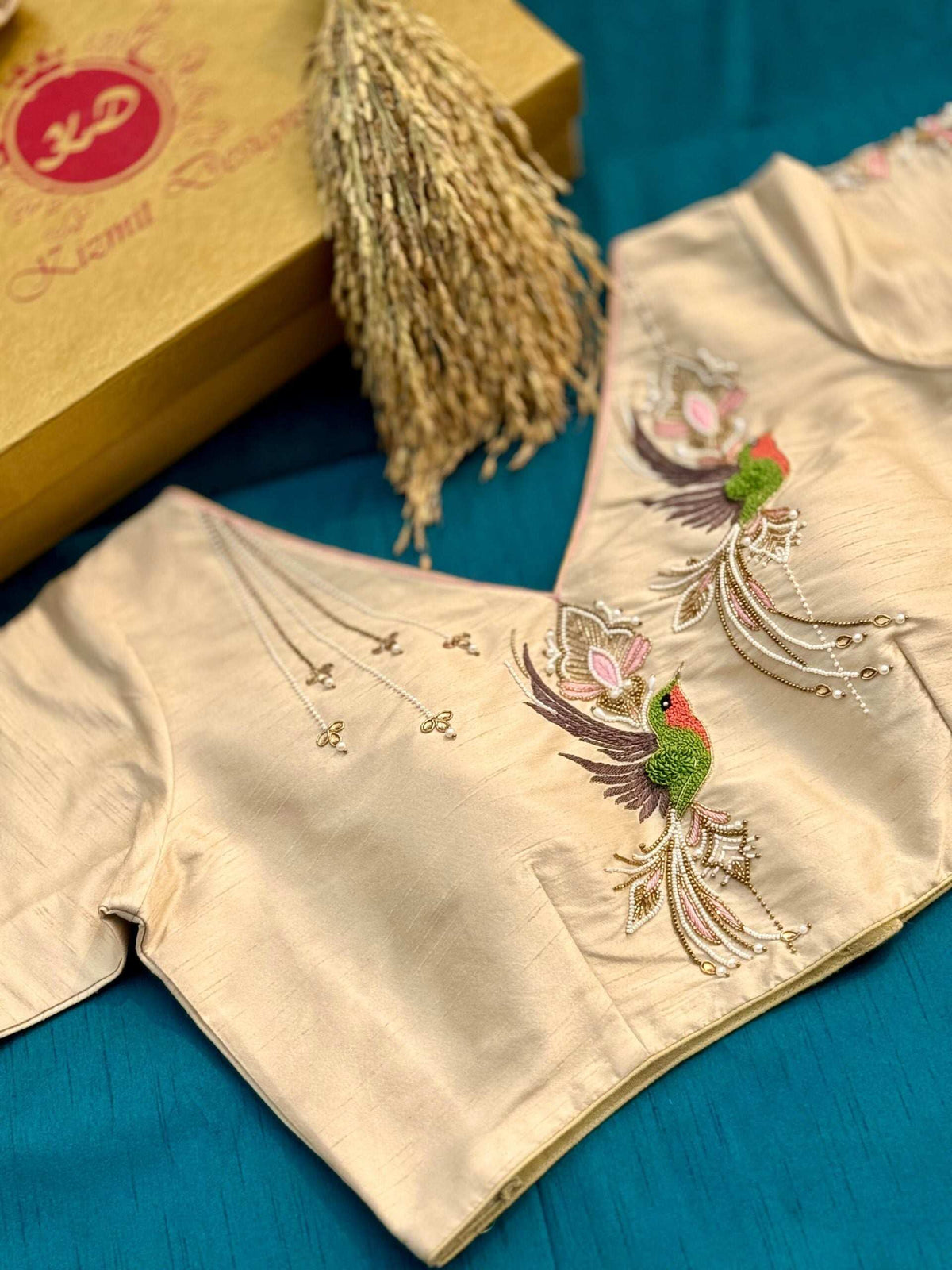 Ivory blouse styled on teal fabric beside a Kizmit Designs box, bird motif in view