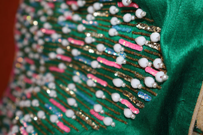 Angled close-up of the beaded yoke edge where it meets the plain green silk