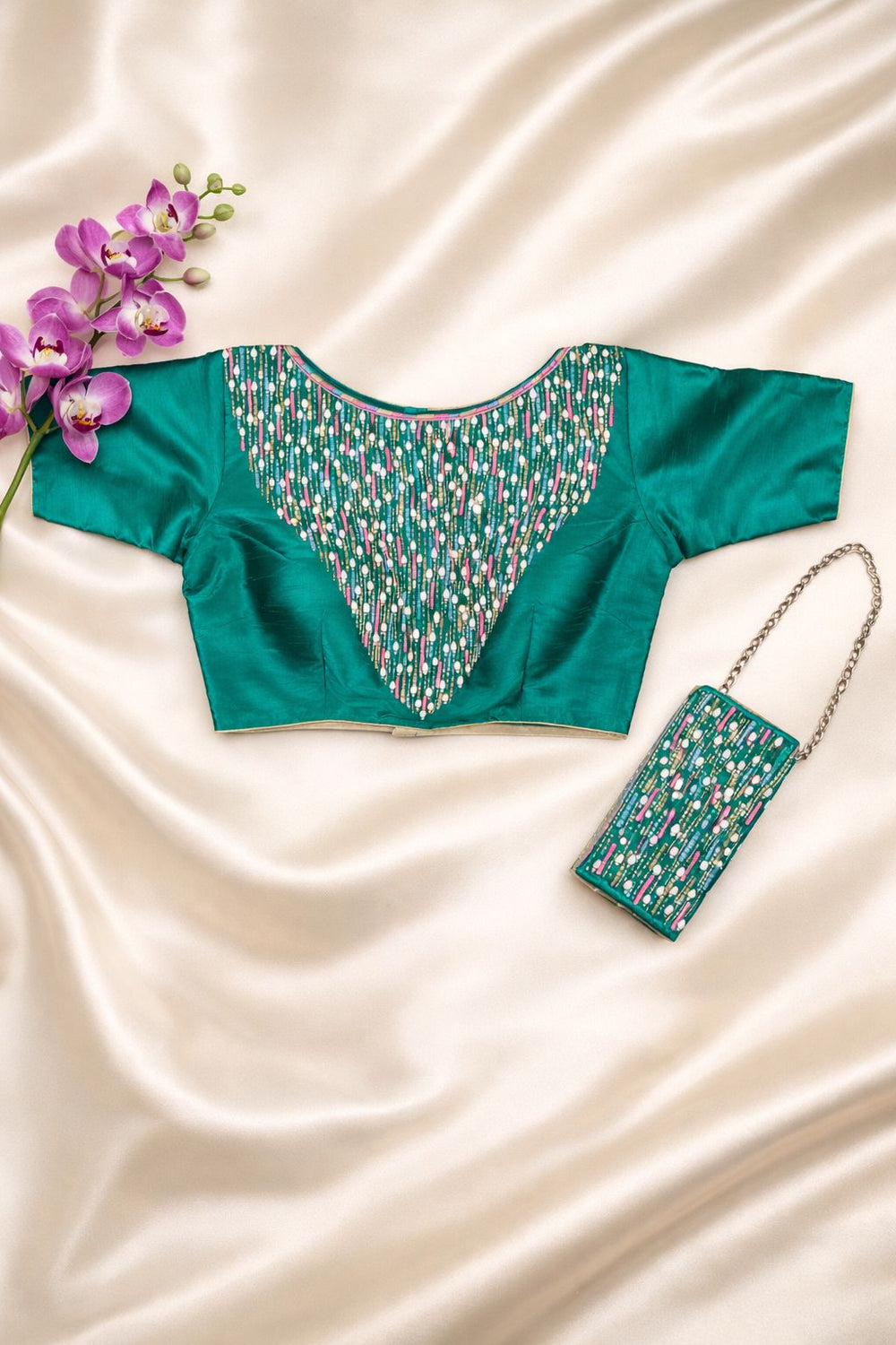 Teal green blouse with pearl and sequin embroidered yoke, laid flat with a matching mobile sling bag