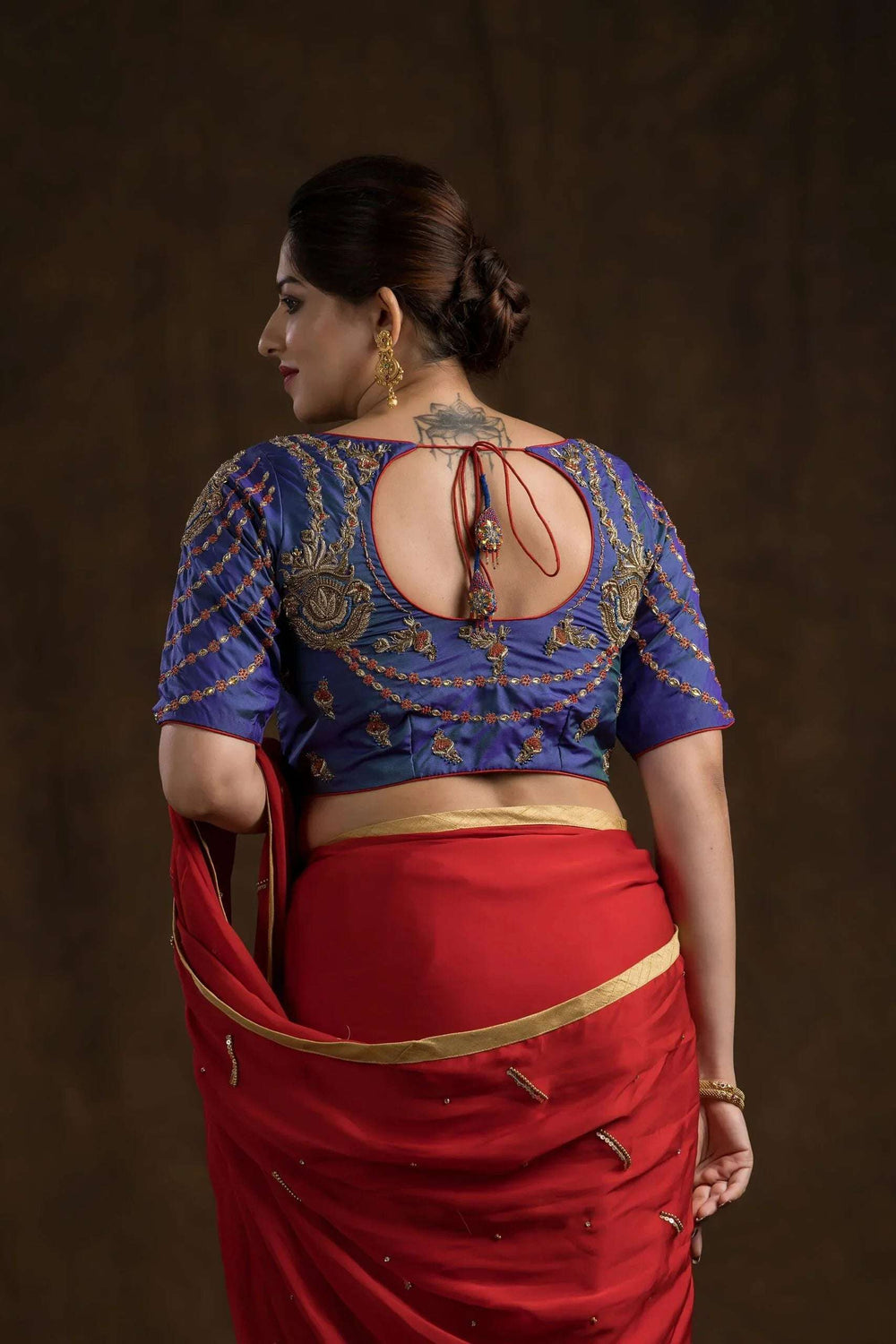Back view close-up, round cut-out framed by gold zari flowers and scalloped motif rows