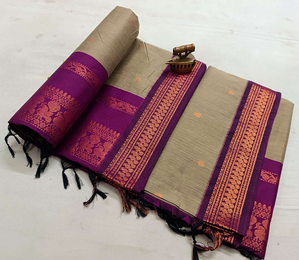 Beige saree body with a purple zari border and copper bootis, folded flat