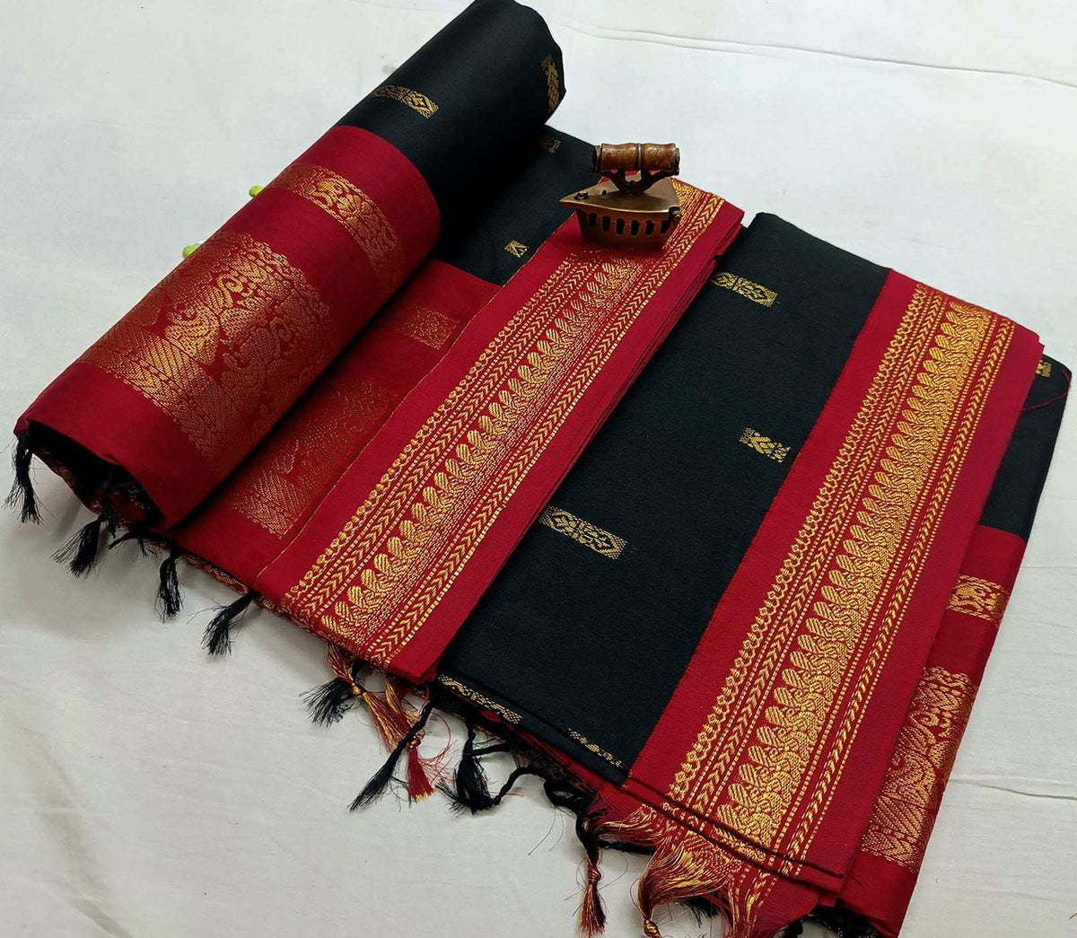 Black saree folded to show the maroon contrast border and gold zari bands