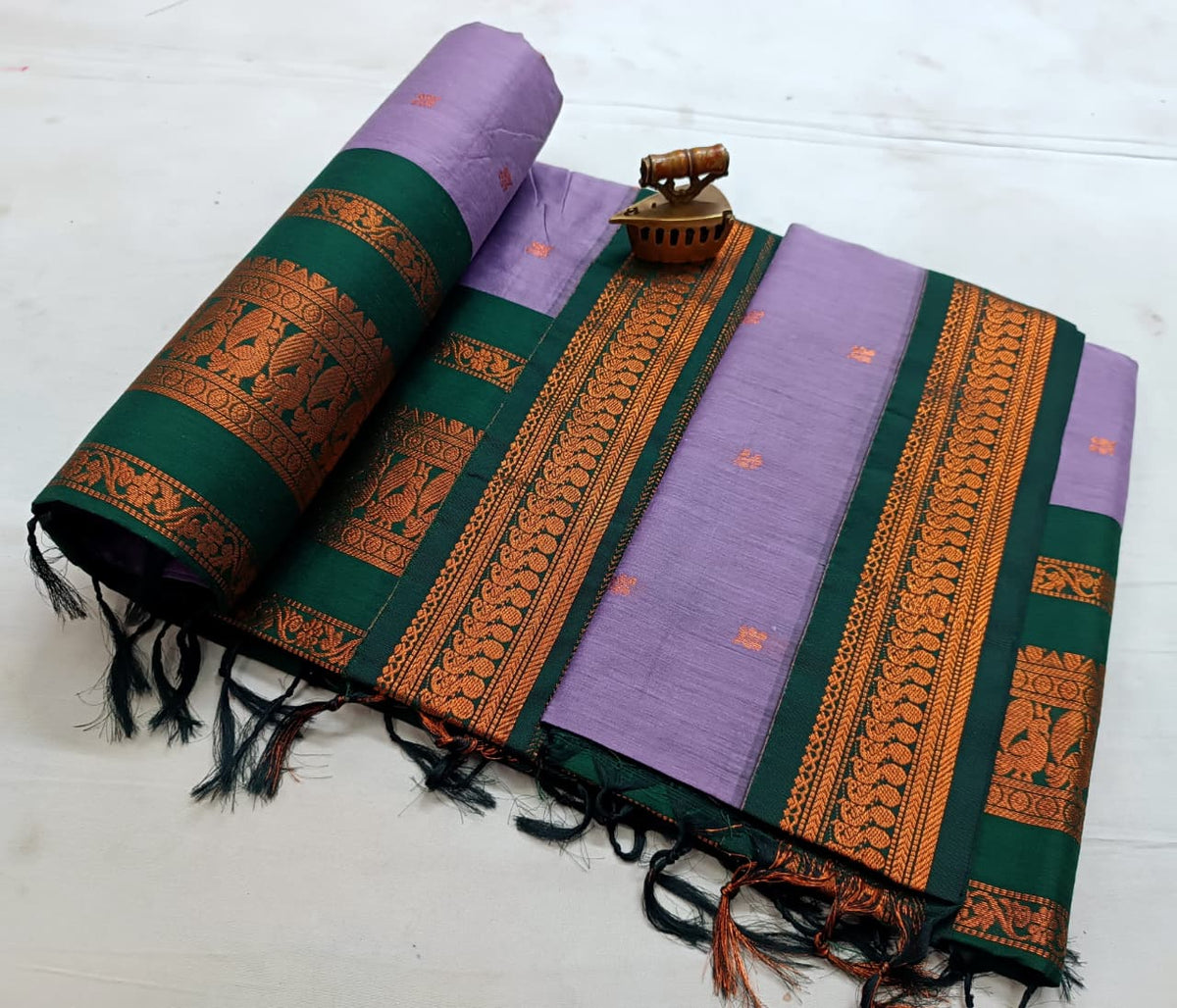 Lilac saree with dark green border in copper zari and small orange bootis on the body