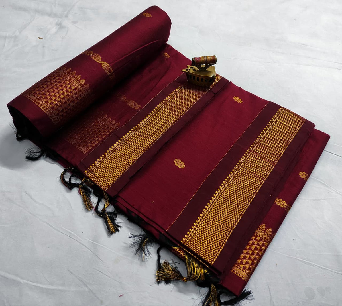 Deep maroon saree with gold zari bootis and a tone-on-tone woven border, spread flat