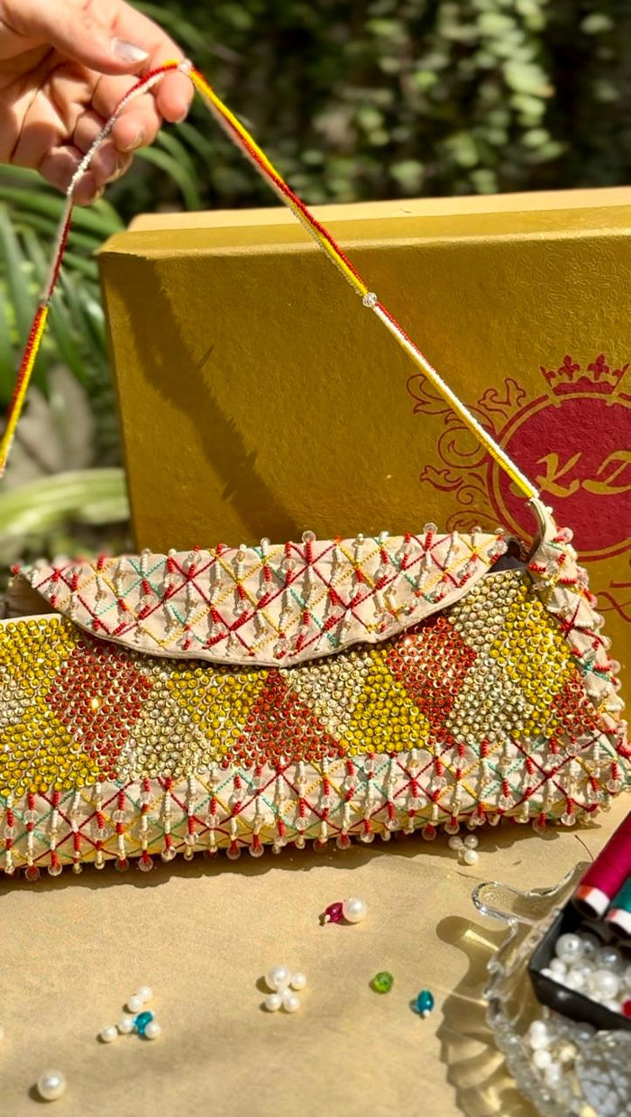 Hand lifting the clutch by its multicoloured beaded strap, close-up of the flap