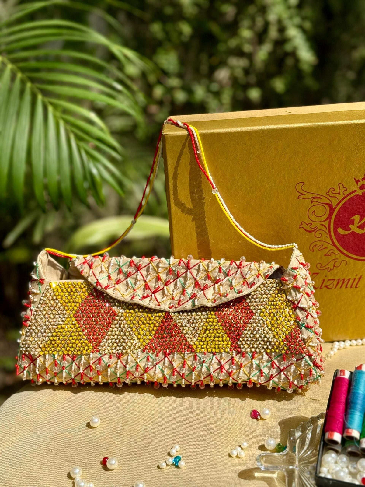 Hand-embroidered clutch standing upright, beaded diamond pattern and scalloped bead edge