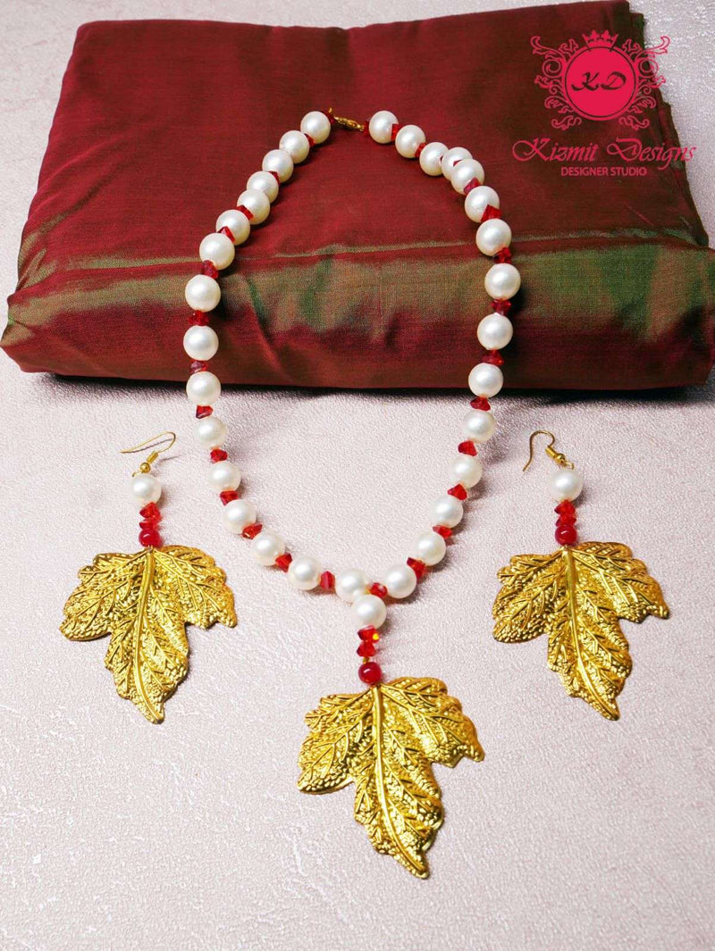 Pearl and red bead necklace with gold leaf pendant and matching earrings, flat lay