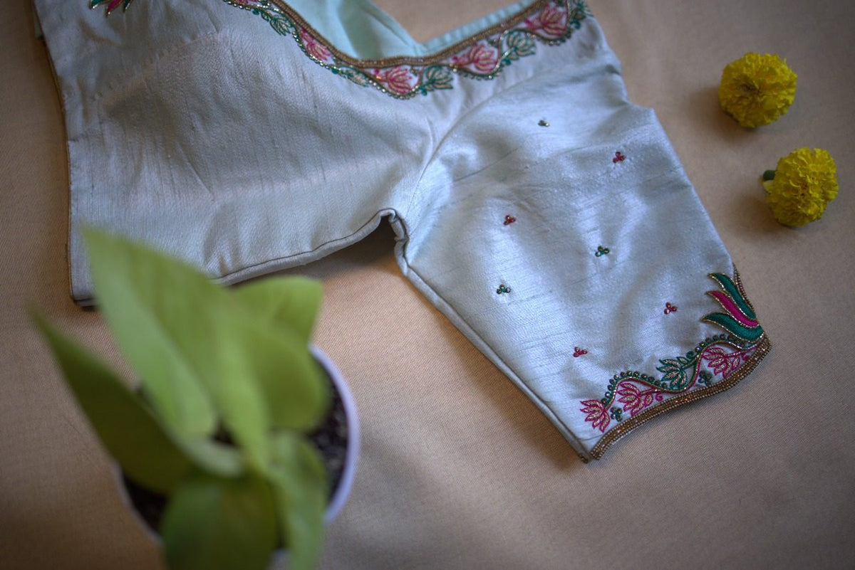 Blouse laid at an angle, sleeve hem lotus border and scattered bootis in view