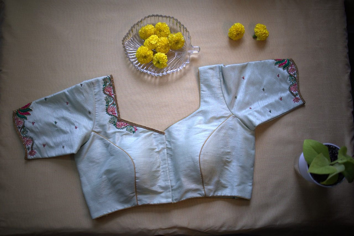 Front of the powder blue blouse laid flat, V neckline with hook closure and short sleeves