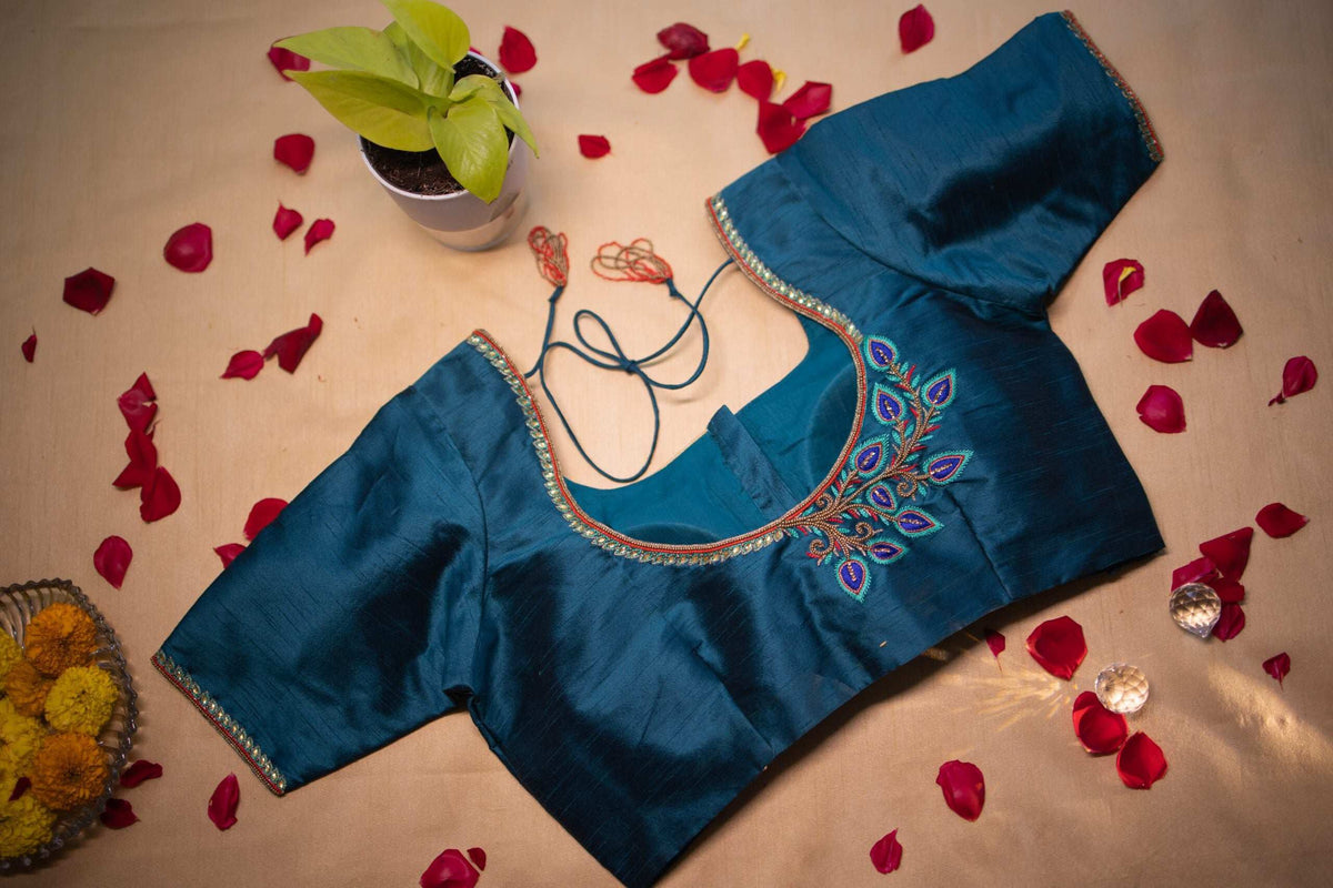 Peacock feather embroidery worked in blue and green on the teal blouse shoulder