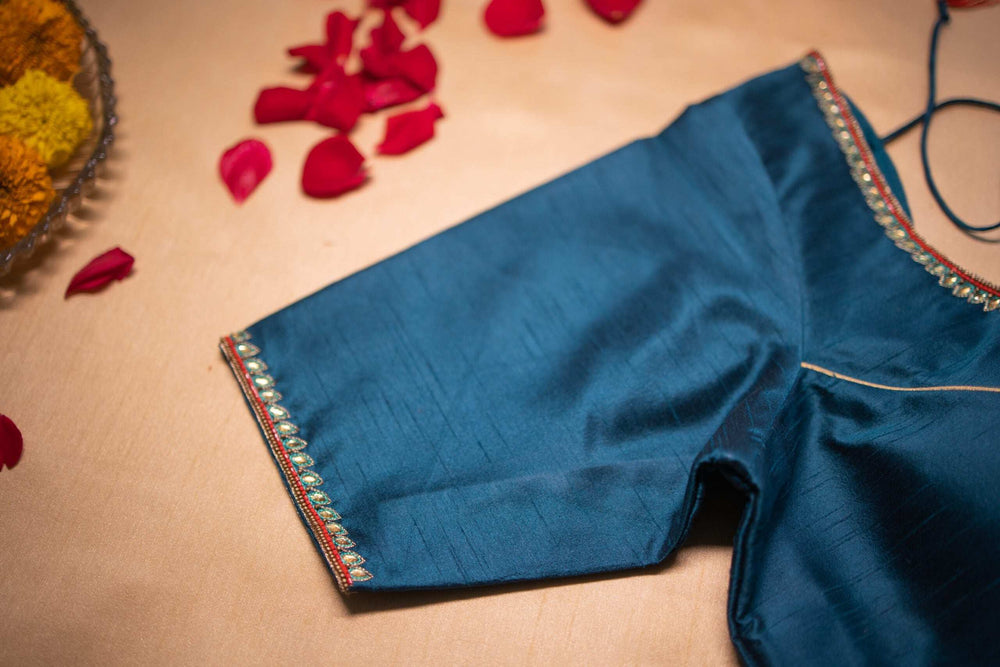 Sleeve hem of the teal blouse edged with pearls and fine gold piping, close-up