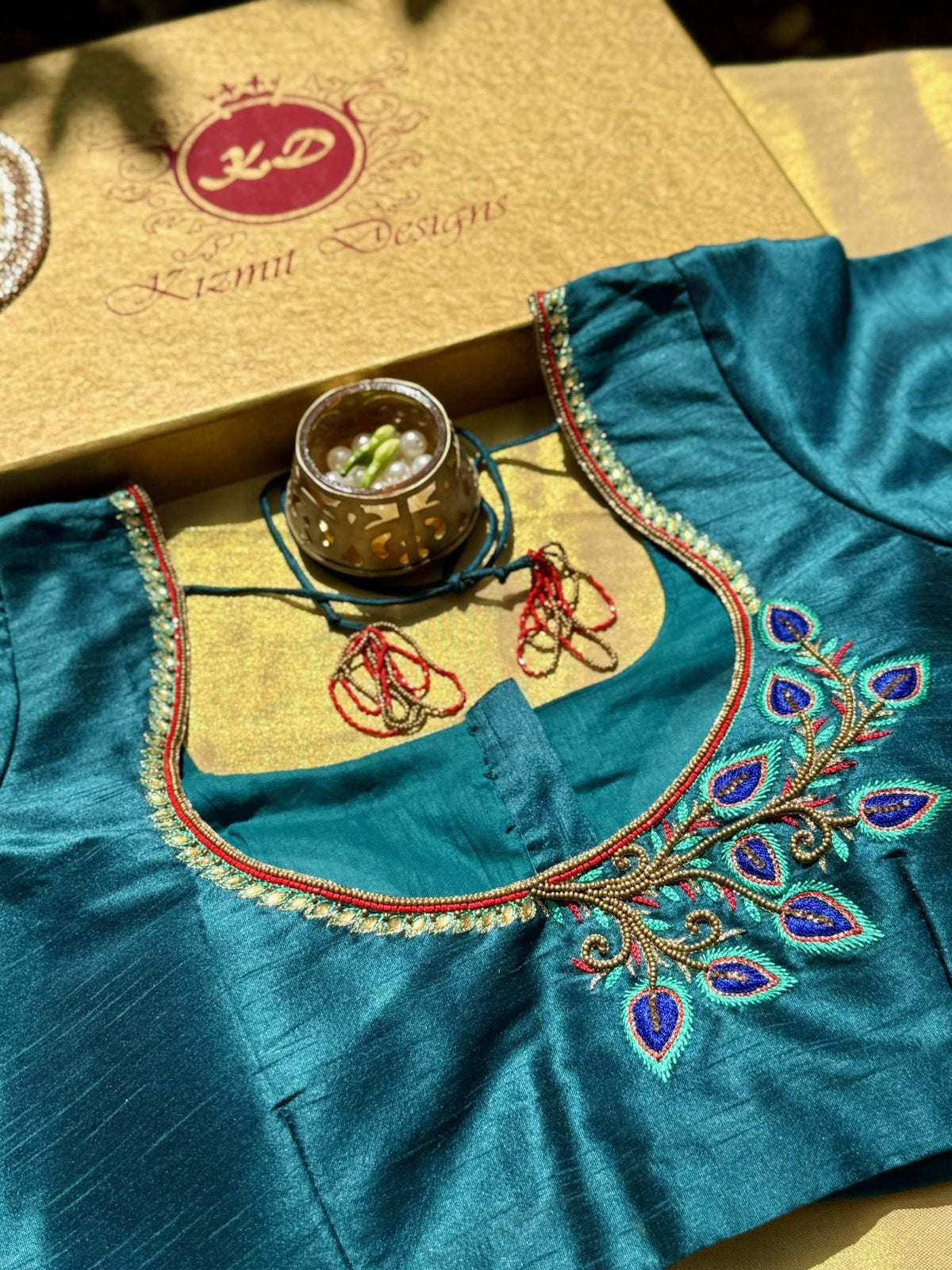 Teal blouse neckline with pearl trim and peacock feather booti, Kizmit box behind